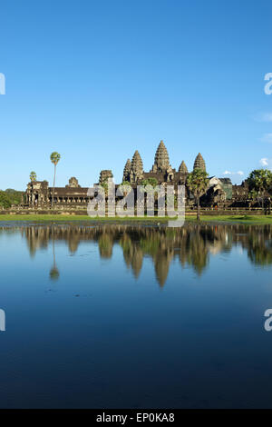Ancien Temple d'Angkor Wat complexe reflétant dans l'eau encore sous ciel bleu Banque D'Images