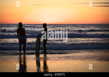 Les jeunes gens debout sur la rive sur Cavancha beach au coucher du soleil à Iquique, Chili Banque D'Images