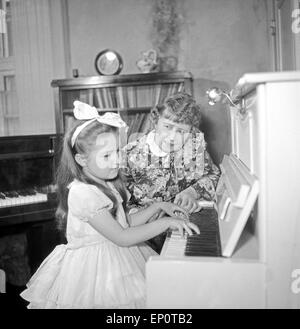 Ein Mädchen spielt une einem Klavier, Hambourg 1956. Une petite fille jouant un piano. Banque D'Images