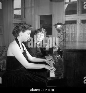 Spielt Eine Frau mit ihrer Klavierlehrerin une einem Flügel, Hambourg 1956. Une jeune femme jouant un duo avec son professeur à une gra Banque D'Images