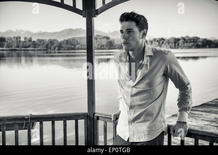 Beau jeune homme sur un lac dans un endroit ensoleillé, jour paisible, sous l'auvent, à la recherche d'un côté Banque D'Images