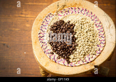 Flocons de grains de café vert et torréfié brun haricots sur tabouret en bois. Banque D'Images