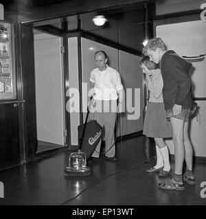 Zwei Kinder der Angestellten schauen beim Bohnern Fußbodens zu, Deutschland des années 1950 er Jahre. Deux enfants regardant un homme poli Banque D'Images