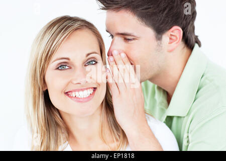 Bel homme murmurer quelque chose à son amie sur un fond blanc. Banque D'Images