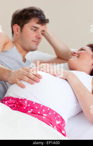 Joyeux caucasian pregnant woman lying on bed avec son mari Banque D'Images