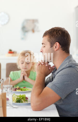 Adorable père et fille priant pendant le déjeuner Banque D'Images
