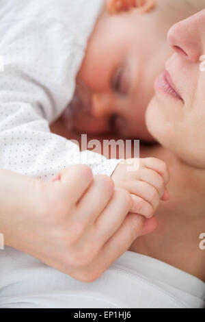 La femme couchée avec son enfant qui est de sucer une sucette Banque D'Images