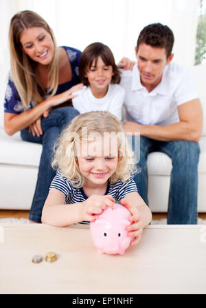 Smiling little girl l'insertion d'une pièce de monnaie pour une tirelire Banque D'Images