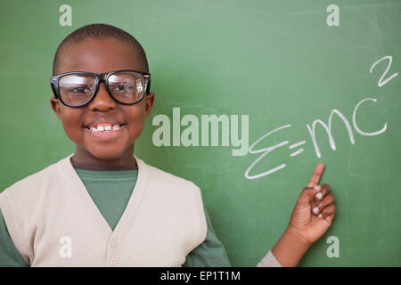 Smart schoolboy montrant le la formule d'équivalence masse-énergie Banque D'Images