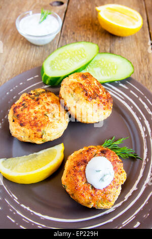 Des croquettes de poisson thaï escalopes) (avec sauce blanche, aneth et citron sur la plaque et table en bois rustique Banque D'Images