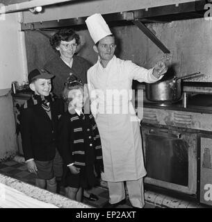 Mme Sterry et ses deux enfants rendre visite à M. Sterry, qui travaille comme assistant cuisinier de l'équipage sur le 'Château' Bloemfontain navire à moteur. Mme Sterry a demandé au Daily Mirror pour photographier son mari avec le navire à l'arrière-plan, comme il devait être transférée lorsque le navire a été vendu aux Grecs. Le Daily Mirror a été le meilleur et a invité la famille pour visiter le navire et Toy Fair à Kensington High Street. Photo montre M. Sterry montrant aux enfants autour de l'équipage Gally à bord du navire. 12 novembre 1959. Banque D'Images