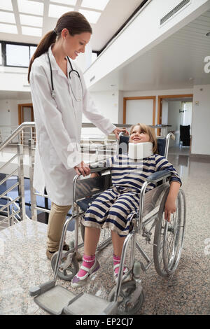 Female doctor smiling at enfant en fauteuil roulant et neck brace Banque D'Images