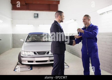 Clé de voiture donnant Mécanicien en secouant la main pour un client Banque D'Images