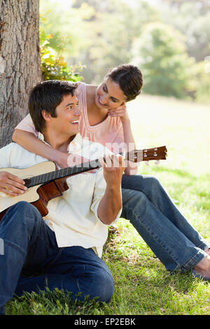 Femme regardant son ami tout en le tenant comme sa joue de la guitare Banque D'Images