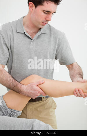 L'examen d'un ostéopathe sérieux la jambe de son patient Banque D'Images
