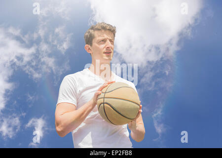 Jeune homme se reposant après épuisement de jeu de basket-ball Banque D'Images