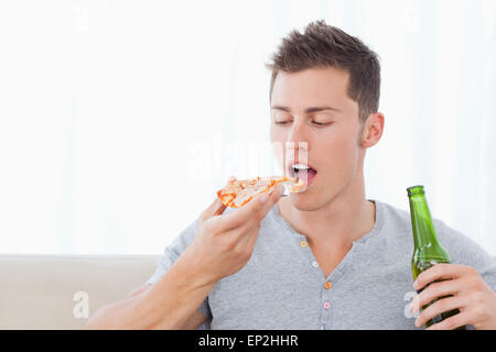 Un homme sur le point de manger une pizza comme il est titulaire de la bière Banque D'Images