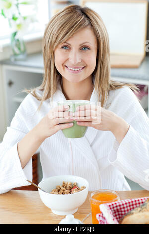 Belle femme tenant une tasse de café de manger les céréales dans la cuisine Banque D'Images