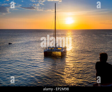 De la Jamaïque, Negril, bateau à voile près de Rick's Cafe à la côte au coucher du soleil Banque D'Images