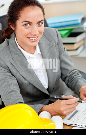 Ravi female architect travaillant dans son bureau, assise à son bureau Banque D'Images