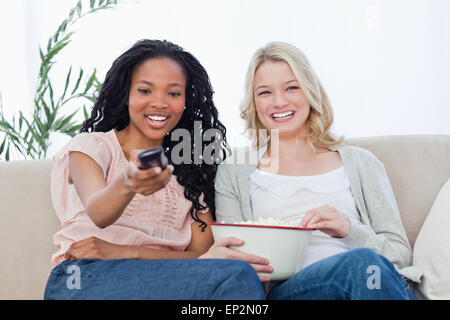 Deux femmes avec des pop-corn et la télécommande d'une télévision Banque D'Images