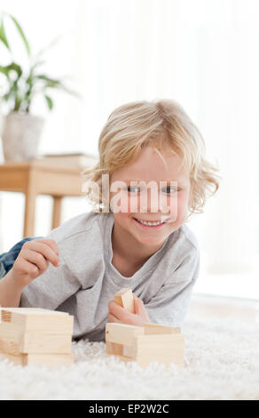 Adorable petit Garçon jouant avec les dominos se trouvant sur le plancher Banque D'Images