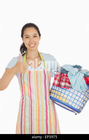 Laughing woman holding panier à linge plein de vêtements sales Banque D'Images