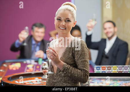 Femme tenant le verre à champagne à mesure que les gens applaudissent derrière elle Banque D'Images