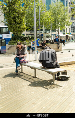 Deux personnes s'assit sur un banc à Bristol à l'aide de téléphones portables Banque D'Images