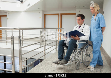 Médecin assis en fauteuil roulant avec des notes d'infirmière Banque D'Images