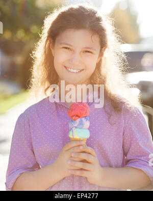 Souriant girl holding ice cream cone dans ses mains à l'extérieur Banque D'Images