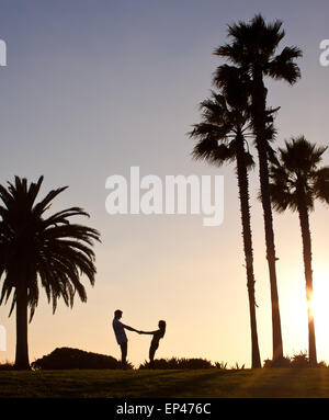 Silhouette d'un couple holding hands at the beach Banque D'Images