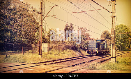 Retro photo aux couleurs d'une locomotive sur le passage à niveau, style vieux film. Banque D'Images
