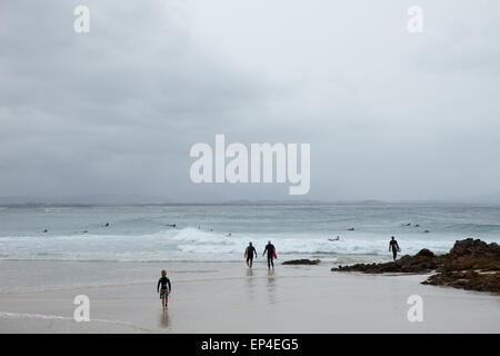 Les surfeurs à pied dehors à l'eau au col à Byron Bay, en Australie. Banque D'Images