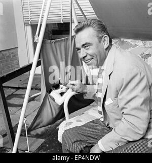 Acteurs et Actrices Deutscher und Entertainer Peter Frankenfeld mit einer Katze auf der Hollywoodschaukel, Deutschland 1960 er Jahre. Banque D'Images