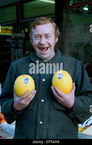 A smiling toothless jardiniers tenant deux pamplemousses à l'extérieur de son magasin à Portsmouth en Angleterre dans les années 90 Banque D'Images