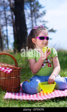 Petite fille avec apple et panier pique-nique à forest Banque D'Images