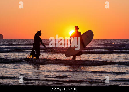 Surfeurs à l'eau à la plage de Perran Sands à Rolvenden, une station balnéaire populaire / Surf resort North Cornwall, Angleterre. Le coucher du soleil. Banque D'Images