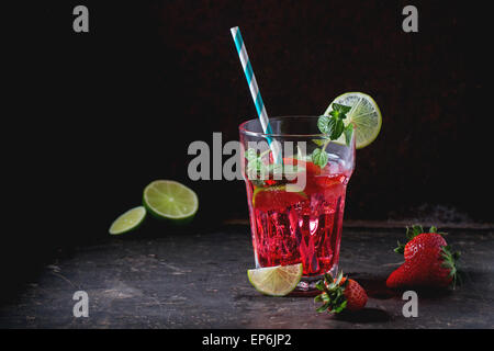 Verre à cocktail rétro avec tubes limonade aux fraises fait maison, servi avec des fraises fraîches, menthe, citron vert et des glaçons sur Banque D'Images