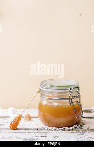 Pot de sauce au caramel fait maison, servi avec des morceaux de sucre sur la table en bois Banque D'Images