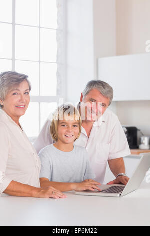 Les grands-parents et enfant looking at camera with a laptop Banque D'Images