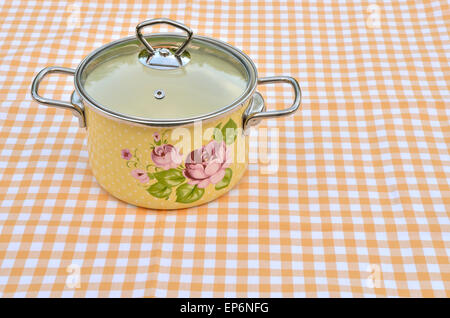 Cocotte au motif floral situé sur la nappe blanche et jaune Banque D'Images