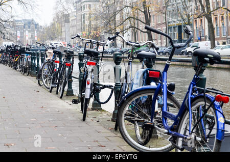 Les vélos garés le long d'un canal dans le centre-ville d'Amsterdam, Pays-Bas Banque D'Images