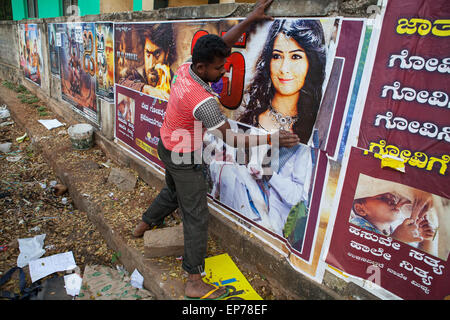 L'homme colle film de Bollywood posters sur un mur, Hassan Banque D'Images