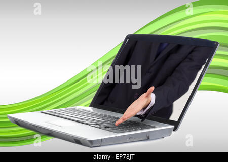 Businessman reaching out from laptop for handshake Banque D'Images