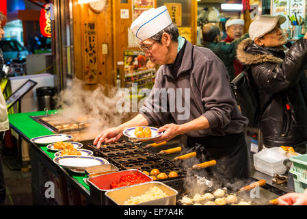 Préparer les chefs japonais et d'autres grignotines takoyaki à un décrochage, à Osaka au Japon. Banque D'Images