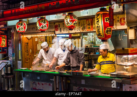 Préparer les chefs japonais et d'autres grignotines takoyaki à un décrochage, à Osaka au Japon. Banque D'Images