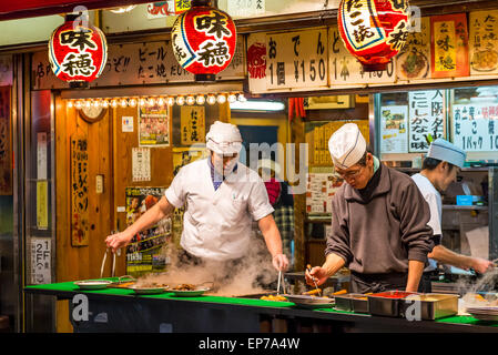 Préparer les chefs japonais et d'autres grignotines takoyaki à un décrochage, à Osaka au Japon. Banque D'Images