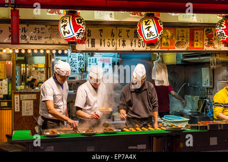 Préparer les chefs japonais et d'autres grignotines takoyaki à un décrochage, à Osaka au Japon. Banque D'Images