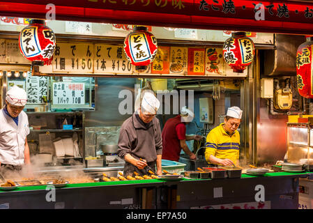 Préparer les chefs japonais et d'autres grignotines takoyaki à un décrochage, à Osaka au Japon. Banque D'Images